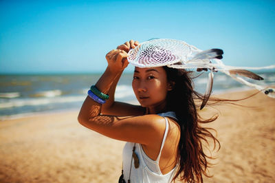 Side view of young woman drinking straw at beach