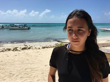 Portrait of woman standing on beach against sky