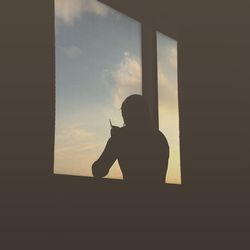 Silhouette of man sitting at window