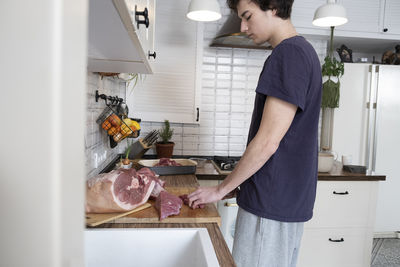 Real men cutting fresh raw meat on board in white kitchen. preparing pork meat, cooking.