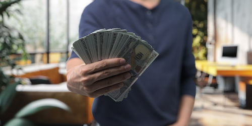 Midsection of man holding paper currency