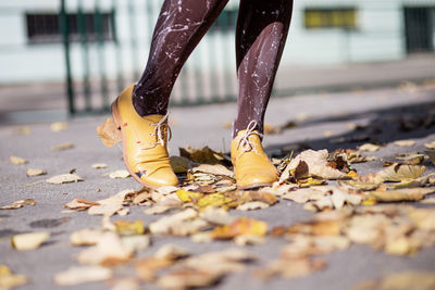 Woman's legs in yellow shoes on autumn leaves