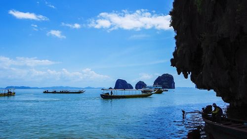 Boats in sea against cloudy sky