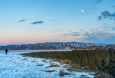 Scenic view of snow covered mountains against sky during sunset