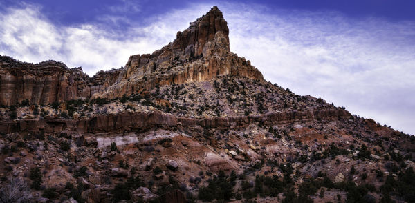 Low angle view of rock formations in mountain against cloudy sky