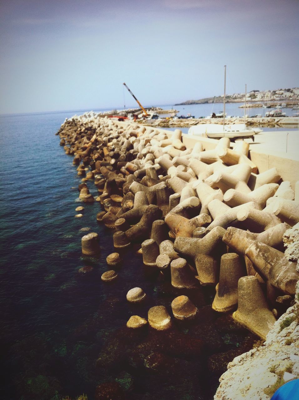 sea, water, beach, clear sky, horizon over water, shore, tranquility, nature, tranquil scene, large group of objects, wood - material, sky, abundance, scenics, stone - object, outdoors, pier, day, no people, sand