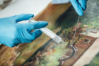 Conservator restoring an old oil painting, revitalizing canvas with syringe