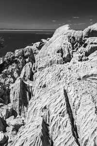 Scenic view of rocks on shore against sky