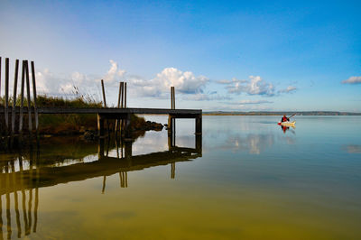 Reflection of man in lake against sky