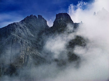 Scenic view of fog over mountain against sky