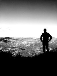 Rear view of silhouette man standing on mountain against sky