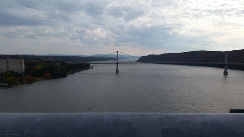 Bridge over river against cloudy sky