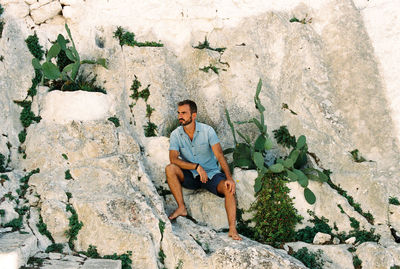 Young man sitting on rock