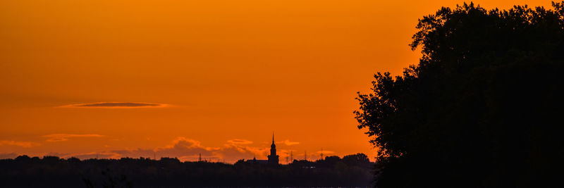 Silhouette trees against orange sky