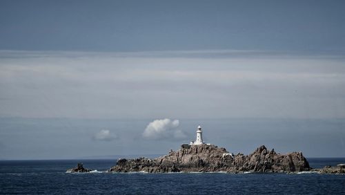 Lighthouse by sea against sky