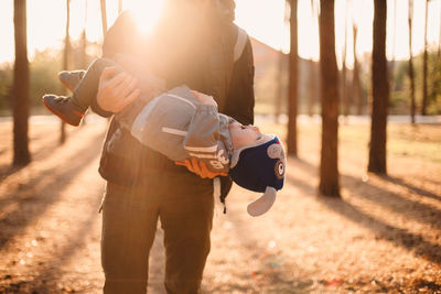 Father playing with son outdoors in park during sunny day in autumn