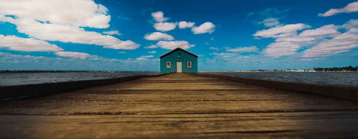 Surface level of wooden pier at beach against sky