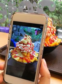 Cropped image of hand photographing ice cream at restaurant