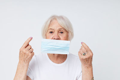 Portrait of smiling young woman holding paper currency against white background