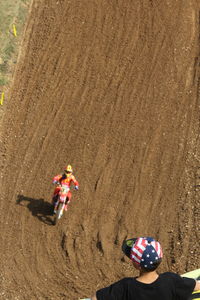 Rear view of boy looking at biker riding motorcycle on dirt road