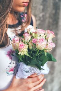 Midsection of woman holding rose bouquet