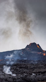 Smoke emitting from volcanic mountain against sky