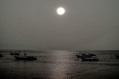 Boats in sea at sunset