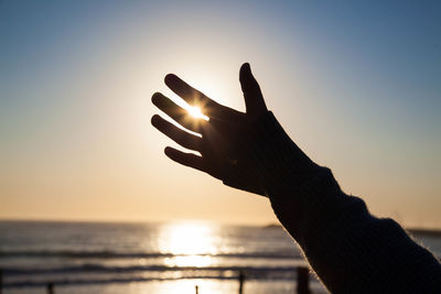 Sunlight through fingers against sky