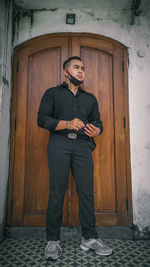 Portrait of young man standing against closed door