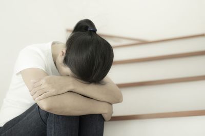 Rear view of woman sitting on wall