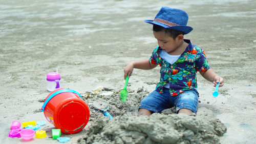 Boy playing with toys on sand at beach