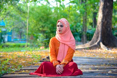 Full length of a young woman sitting on tree
