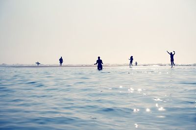 People at beach against clear sky