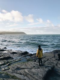 Rear view of man standing on beach against sky