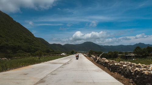 Rear view of people on road against sky