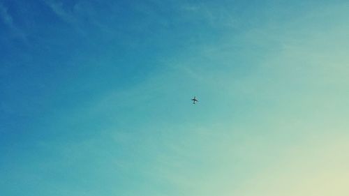 Low angle view of airplane flying against blue sky
