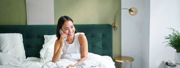 Young woman sitting on bed at home