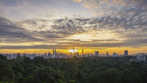 Panoramic view of trees and buildings against sky during sunset