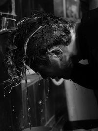 Side view of man washing face in bathroom