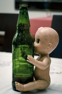 Close-up of alcoholic drink in bottle by doll on table