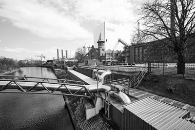 Bridge over river by buildings in city against sky