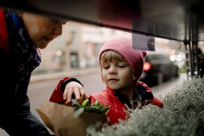 Senior woman buying plants with grandson in city