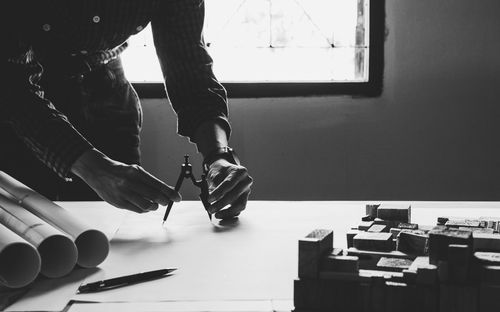 Midsection of architect working on blueprint at desk in office