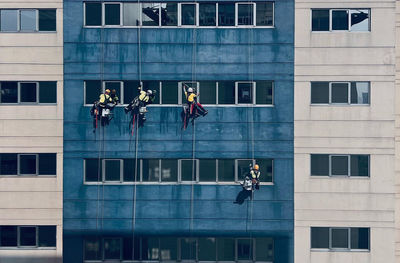 Team of workers painting wall high rise building. painters are painting exterior office buildings. 