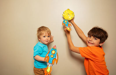 Portrait of smiling girl holding gift against wall