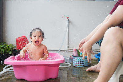 Happy boy sitting on wet table in bathroom