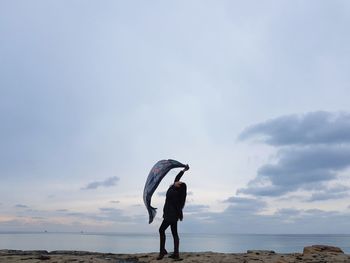 Full length of woman with scarf while standing on beach against sky