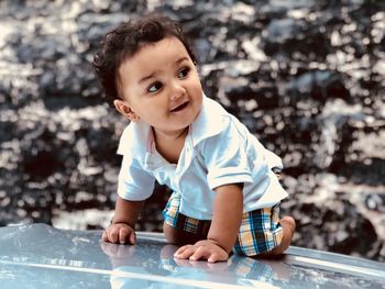 Close-up of cute baby boy kneeling on car