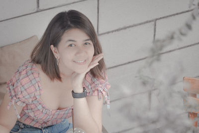 Portrait of smiling young woman against wall