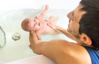 Side view of shirtless baby boy washing hands